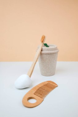 Zero waste concept, eco friendly. A mug for drinks, wooden toothbrush and comb. Front view