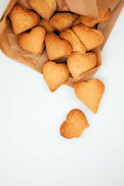 Shortbread cookies in the form of hearts in a brown paper bag on a white table. Top view