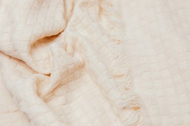 Textured background for design. Light beige knitted fabric with a checkered pattern, top view