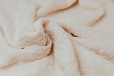 Textured background for design. Light beige knitted fabric with a checkered pattern, top view