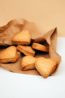 Shortbread cookies in the form of hearts in a brown paper bag on a white table. Front view