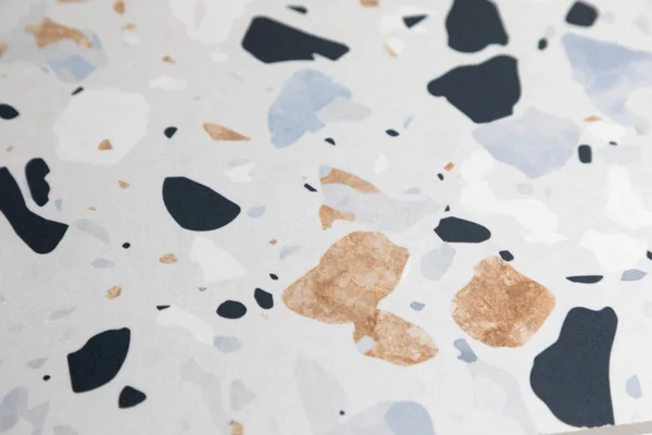 Light gray ceramic surface with mosaic colors in black, brown and blue. Abstract background. Top view