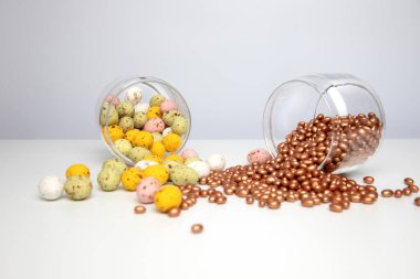 Chocolate colorful decorative eggs in a glass jar on a white background. Happy Easter. Front view