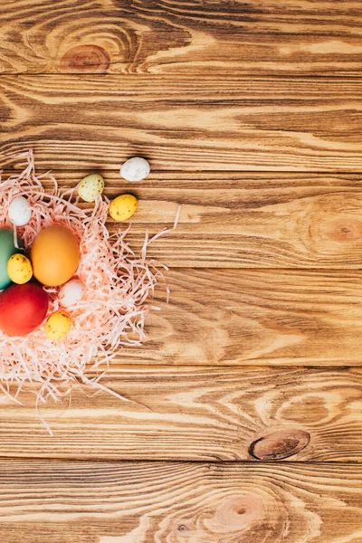 stock image Colored eggs of different sizes on a brown wooden background. Symbol of the Easter holiday. Easter background, flat lay