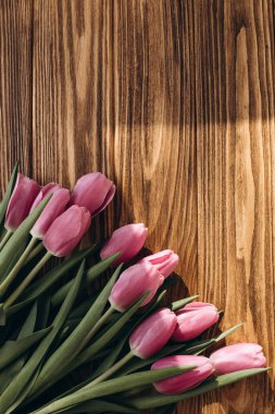 Pale pink delicate tulips on a brown wooden background. Spring background with a bouquet of flowers. Flat lay