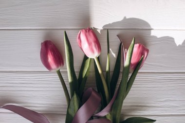 Pale pink delicate tulips on a white wooden background. Spring background with a bouquet of flowers. Top view