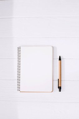 İmza şablonu. Açık bir not defteri, boş bir sayfa ve beyaz ahşap arka planda ekolojik malzemelerden yapılmış bir kalem. Düz yatıyordu