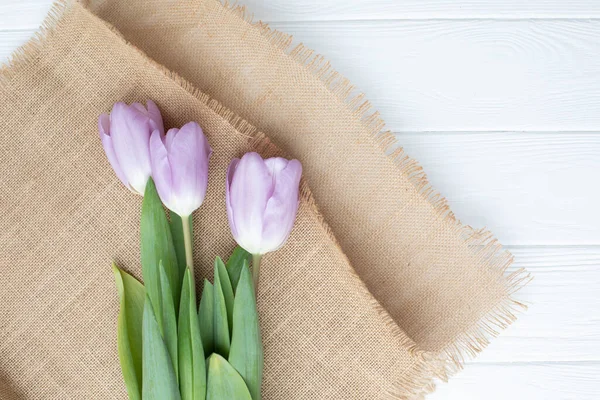 stock image White delicate tulips on a white wooden background. Spring background with a bouquet of flowers. Top view