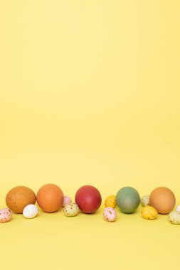 Sarı arka planda renkli yumurtalar. Paskalya bayramının sembolü. Paskalya geçmişi. Ön görünüm