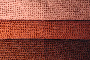 Background for design. Waffle fabrics in orange, brown and pink with fringes. Top view