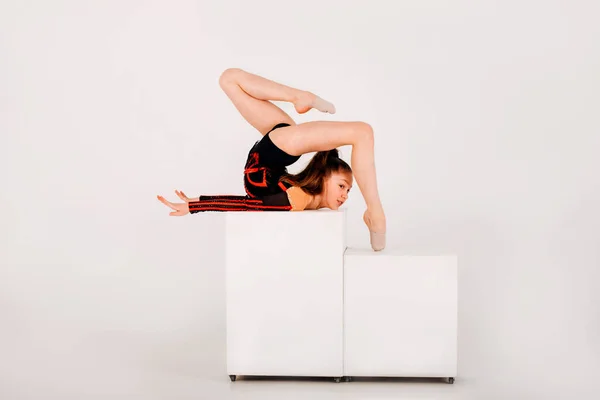 Dívka Gymnastka Černém Trikotu Dělá Triky Bílé Kostce Bílém Pozadí — Stock fotografie