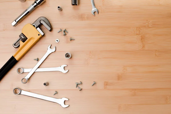 A set of working tools, an adjustable spanner, a screwdriver, wrenches for repair on a brown bamboo, wooden background. Flat lay
