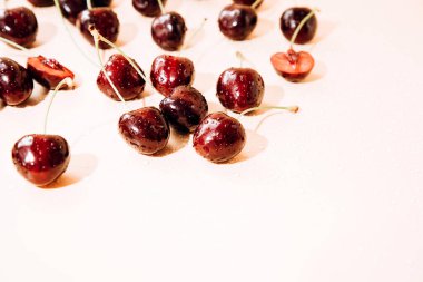 A large cherry with water drops close up on a light orange background in sunlight, selective focus. Top view