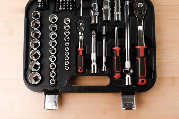 Stock image A set of working tools in black plastic bag, a screwdriver, adjustable spanner, sockets for repair on a bamboo, wooden background. Top view