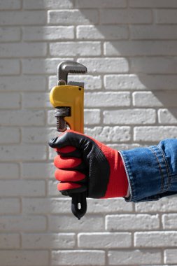 Tamir için kullanılan aletler. Elinde sarı İngiliz anahtarı tutan kot pantolonlu bir adam. Ön görünüm
