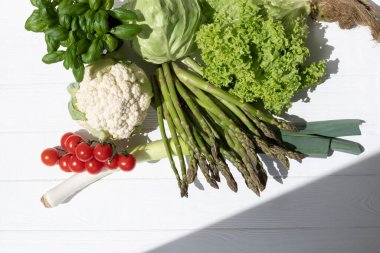 Taze sebze, kuşkonmaz, domates, lahana, karnabahar, yeşil salata, beyaz ahşap arka planda bazilika. Düz yatıyordu