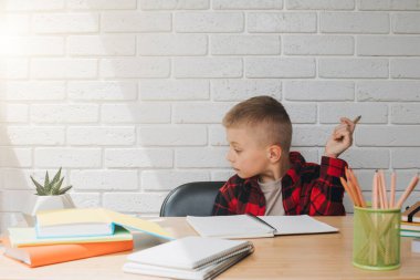 Konsepti okula geri götür. Öğrenim sürecinde olan bir çocuk, unigami, defter ve kalemlerle aynı masada oturuyor. Ön görünüm