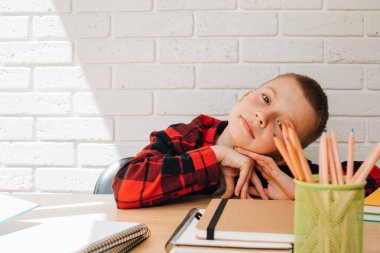 Konsepti okula geri götür. Öğrenim sürecinde olan bir çocuk, unigami, defter ve kalemlerle aynı masada oturuyor. Ön görünüm