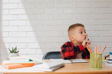 Konsepti okula geri götür. Ders çalışma sürecinde olan bir çocuk kitaplar, defterler ve kalemlerle bir masada oturur. Ön görünüm
