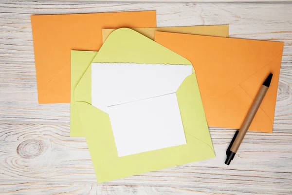 Hellgrüne Orangefarbene Gelbe Umschläge Und Eine Weiße Textkarte Auf Weißem — Stockfoto