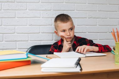 Konsepti okula geri götür. Ders çalışma sürecinde olan bir çocuk kitaplar, defterler ve kalemlerle bir masada oturur. Ön görünüm