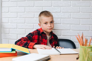Konsepti okula geri götür. Öğrenim sürecinde olan bir çocuk, unigami, defter ve kalemlerle aynı masada oturuyor. Ön görünüm