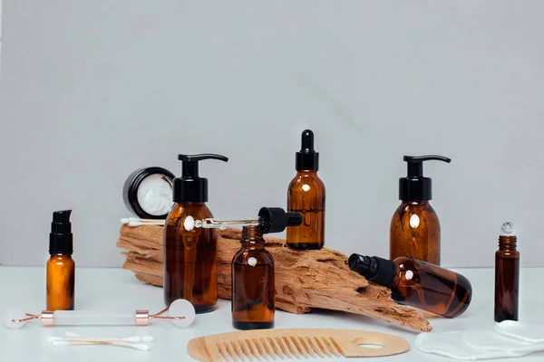 Amber bottles with facial treatment on a wooden stand on a white table. Front view