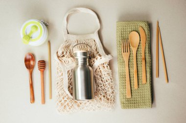 Different fabric bags for storage on a gray background. Eco bags for multiple use. A reusable straws, wooden cutlery. Flat lay