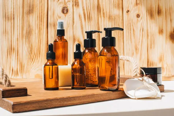 Amber bottles with facial cosmetics, liquid on a wooden tray on the wooden background. Flat lay
