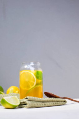 Beton bir arka planda portakallı limon ve cam şeffaf bardaklarda limon iç. Buzlu limonata. Ön görünüm