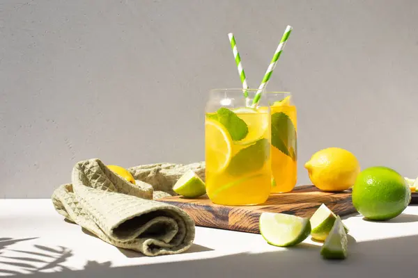 Beton bir arka planda portakallı limon ve cam şeffaf bardaklarda limon iç. Buzlu limonata. Ön görünüm
