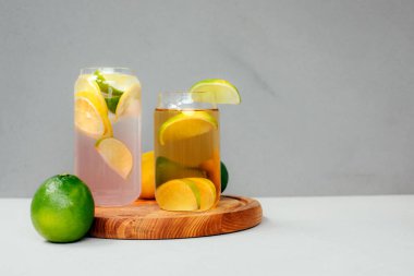 Beton bir arka planda portakallı limon ve cam şeffaf bardaklarda limon iç. Buzlu limonata. Ön görünüm