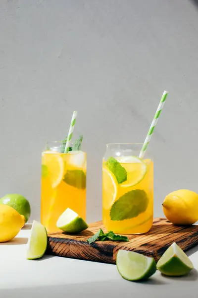 Beton arka planda şeffaf bardaklarda portakallı limon ve limonla iç. Buzlu limonata. Ön görünüm