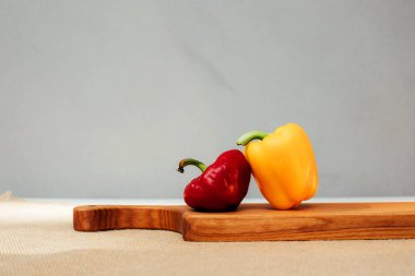 Beton arka planda farklı boyutlarda dolmalık biberler. Bahçe arka planı, dolmalık biber hasadı. Olgunlaşmış kırmızı ve sarı kağıt. Ön görünüm