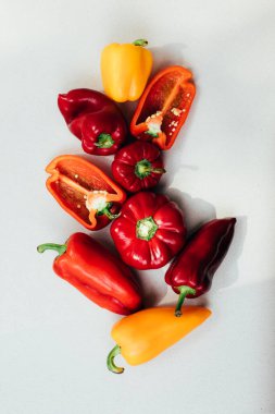 Beton arka planda farklı boyutlarda dolmalık biberler. Bahçe arka planı, dolmalık biber hasadı. Olgunlaşmış kırmızı ve sarı kağıt. Üst görünüm