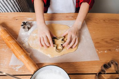 Baba ve oğlu mutfaktaki ahşap masada küçük adam şeklinde kurabiye kesiciyle kurabiye yapıyorlar. Üst görünüm