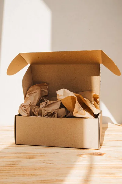 Packaging of eco-materials. Cardboard box and packaging paper on a light background. Concept saving the planet from undetectable debris. Front view