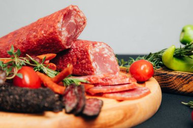 Yuvarlak ahşap bir tabakta farklı tip ve boyutlarda sosis. Tütsülenmiş sosis. Ön görünüm