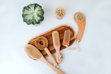 Beyaz arka planda ahşap bir standın üzerinde ahşap saplı fırçalar, çevre dostu ürünler. Düz yatıyordu