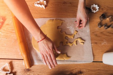 Kadınların elleri, mutfaktaki ahşap bir masada kurabiye şekillendirir. Evde yemek pişirme tatlısı. Üst görünüm