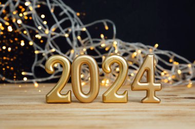 Boşluklu selamlama arkaplanı. Mutlu yıllar kartı. Siyah arka plandaki ahşap bir masada 2024 rakamları. Ön görünüm