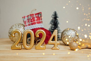Boşluklu selamlama arkaplanı. Mutlu yıllar kartı. Noel oyuncaklarıyla birlikte açık ahşap arka planda 2024 'e benziyor. Ön görünüm