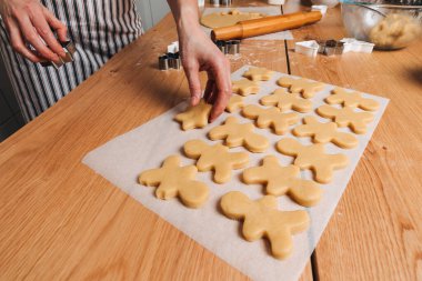 Kadınların ellerini mutfaktaki ahşap bir masada kapayın. Küçük adam ve yıldız şeklinde kurabiye kesiciyle kurabiye yapın. Üst görünüm