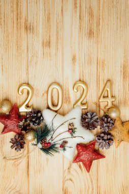 Boşluklu selamlama arkaplanı. Mutlu yıllar kartı. Noel oyuncaklarıyla birlikte açık ahşap arka planda 2024 'e benziyor. Üst görünüm