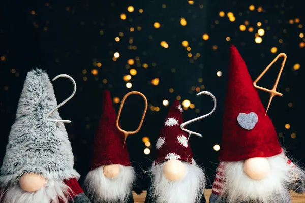 Yeni yıl, Noel geçmişi. 2024 numaralı mum. Ahşap ve siyah arka planda dekoratif küçük noel cüceleri. Ön görünüm