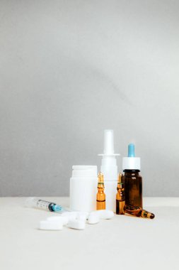 Şişelerde ve tabletlerde, şeffaf plakalarda hafif arka planda tedavi için bir takım ilaçlar. Ön görünüm