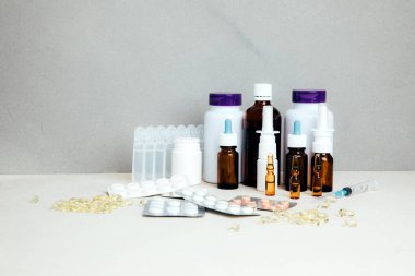 Şişelerde ve tabletlerde, şeffaf plakalarda hafif arka planda tedavi için bir takım ilaçlar. Ön görünüm