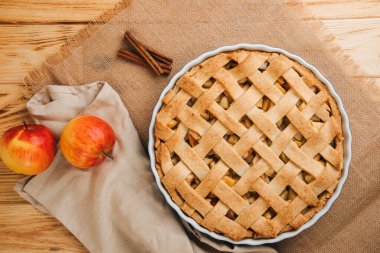 Elmalı turta açık ahşap arka planda, bej bir mutfak havlusuyla mavi formda. Hazır turta. Üst görünüm