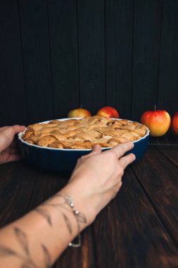 Elmalı turta mavi formda, kadın eli ile koyu ahşap arka planda. Hazır turta. Ön görünüm