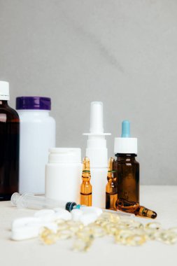 Şişelerde ve tabletlerde, şeffaf plakalarda hafif arka planda tedavi için bir takım ilaçlar. Ön görünüm